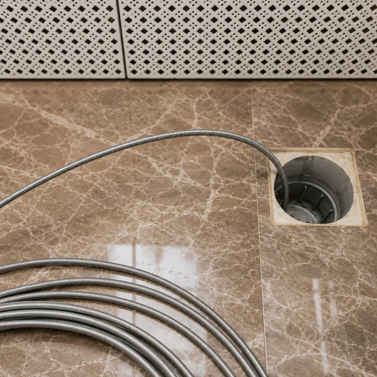 Drain cable fed into a marble bathroom floor drain