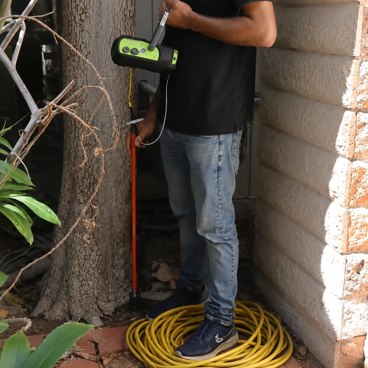 Technician using a ground microphone beside an exterior wall